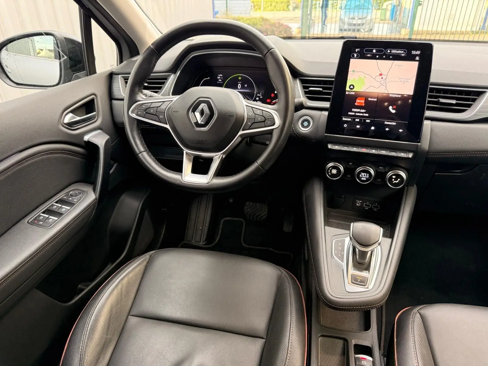 Vue intérieure du poste de conduite du Renault Captur gris Highland 2021, avec volant cuir, écran tactile et levier de boîte auto.