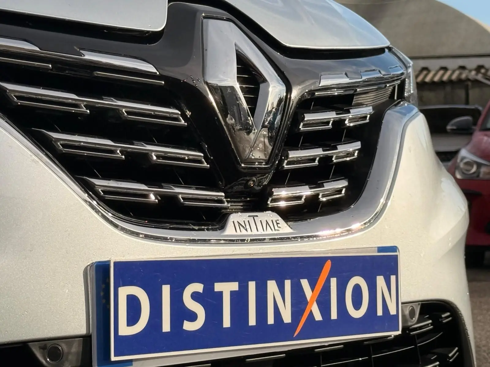 Gros plan sur la calandre noire et chromée d'un Renault Captur gris Highland avec logo et badge Initiale Paris.