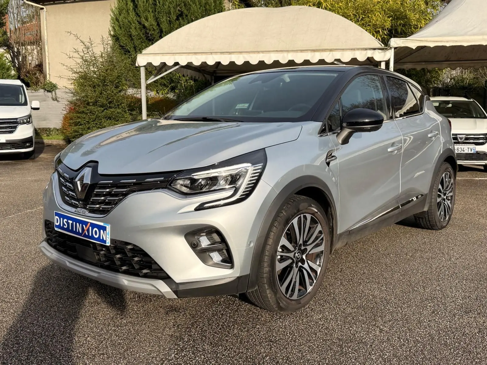 Renault Captur gris Highland en 3/4 avant droit, avec jantes alliage et toit noir contrasté visible en extérieur.