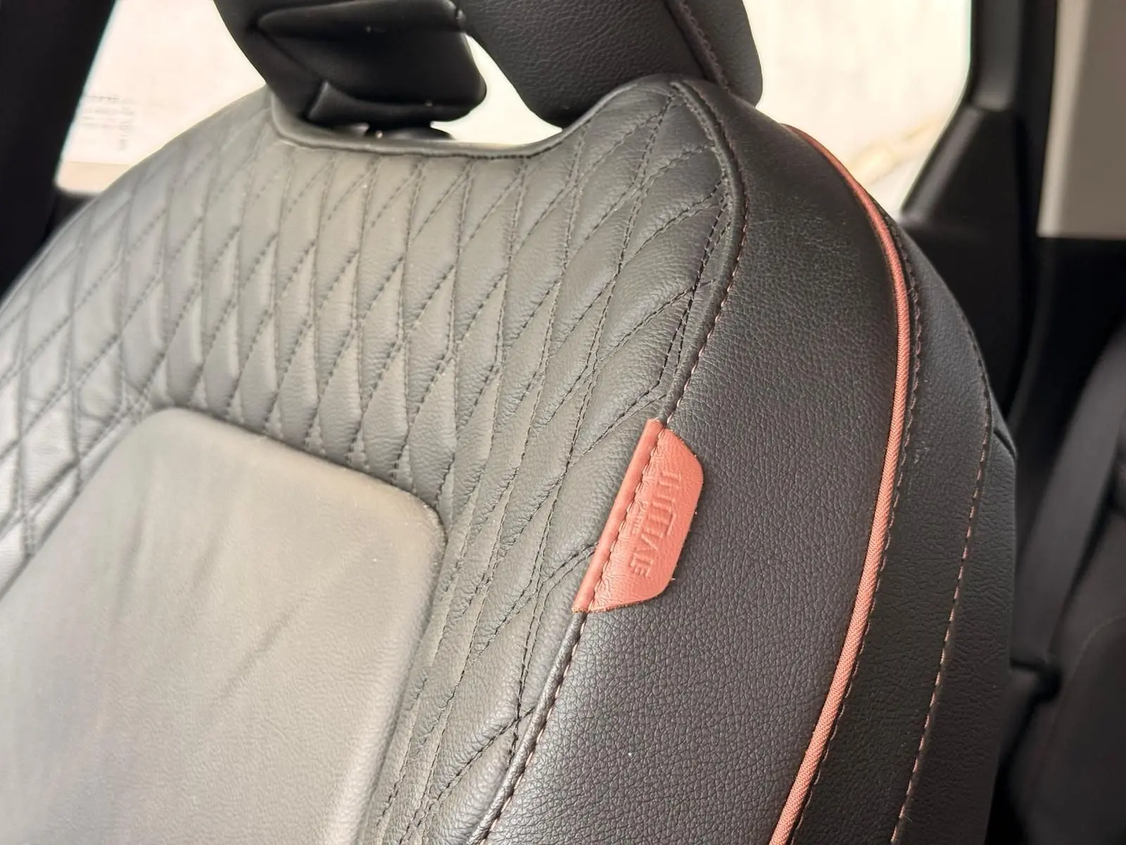 Gros plan sur le siège avant en cuir gris Highland matelassé avec étiquette rouge "Initiale Paris" du Renault Captur hybride 2021.