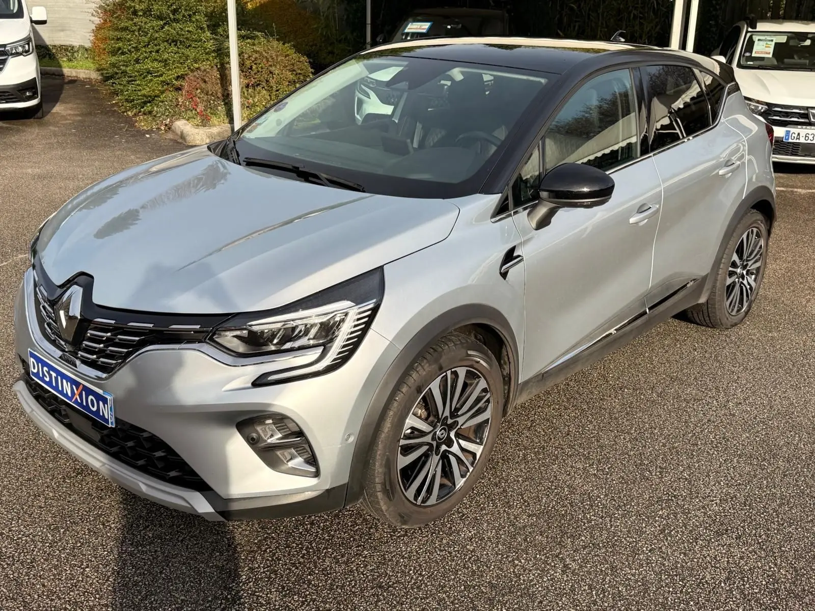 Renault Captur gris Highland en 3/4 avant droit, toit noir contrasté et jantes alliage distinctives.