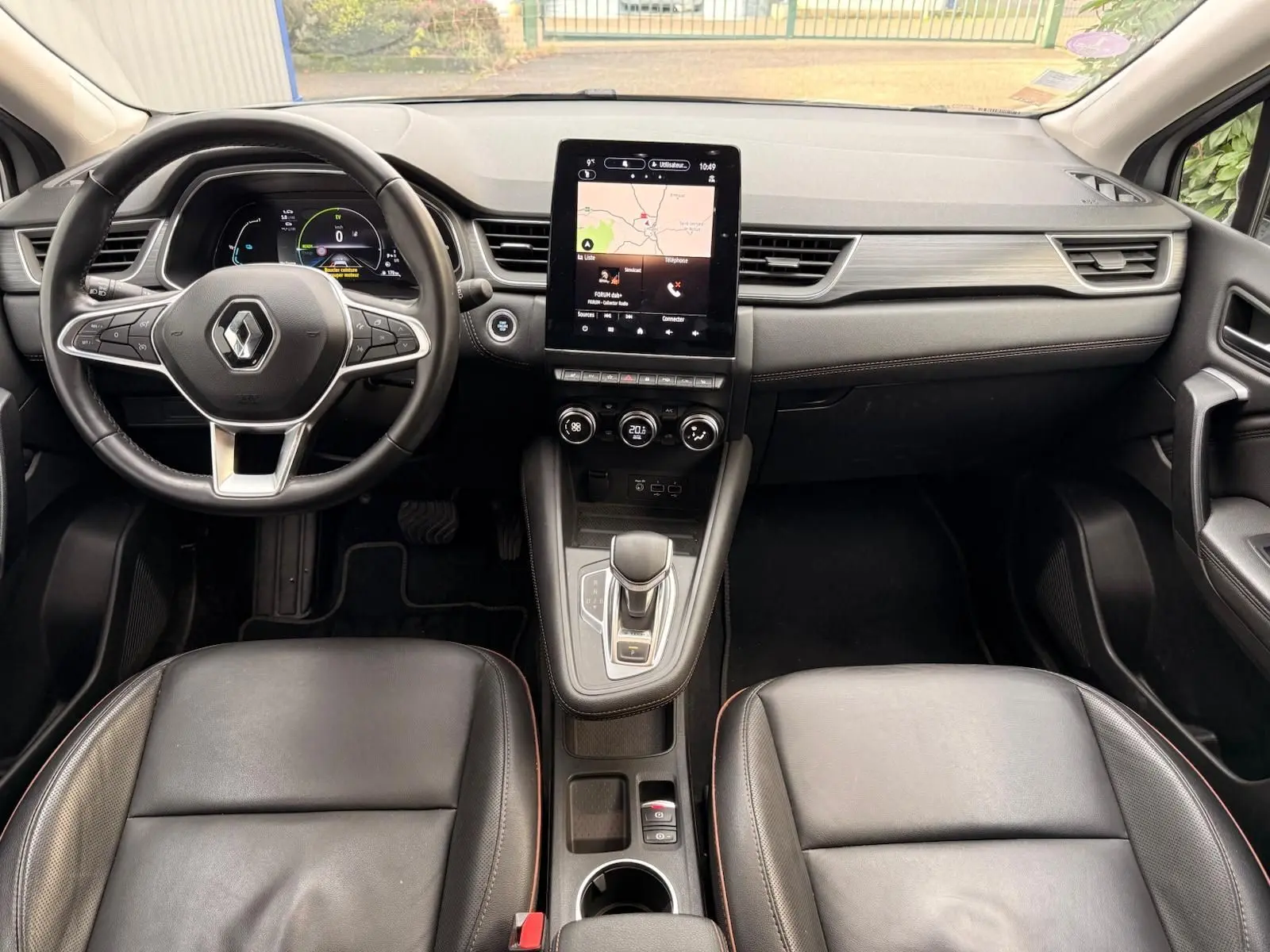 Intérieur du Renault Captur 1.6 E-TECH hybride 2021, vue frontale du tableau de bord avec écran tactile et sièges cuir noirs.