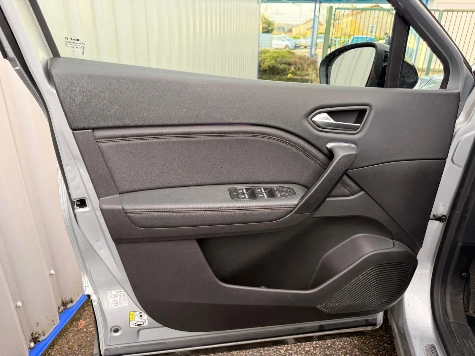 Porte intérieure côté gauche du Renault Captur gris Highland 2021, avec commandes de vitres et poignée intégrée.