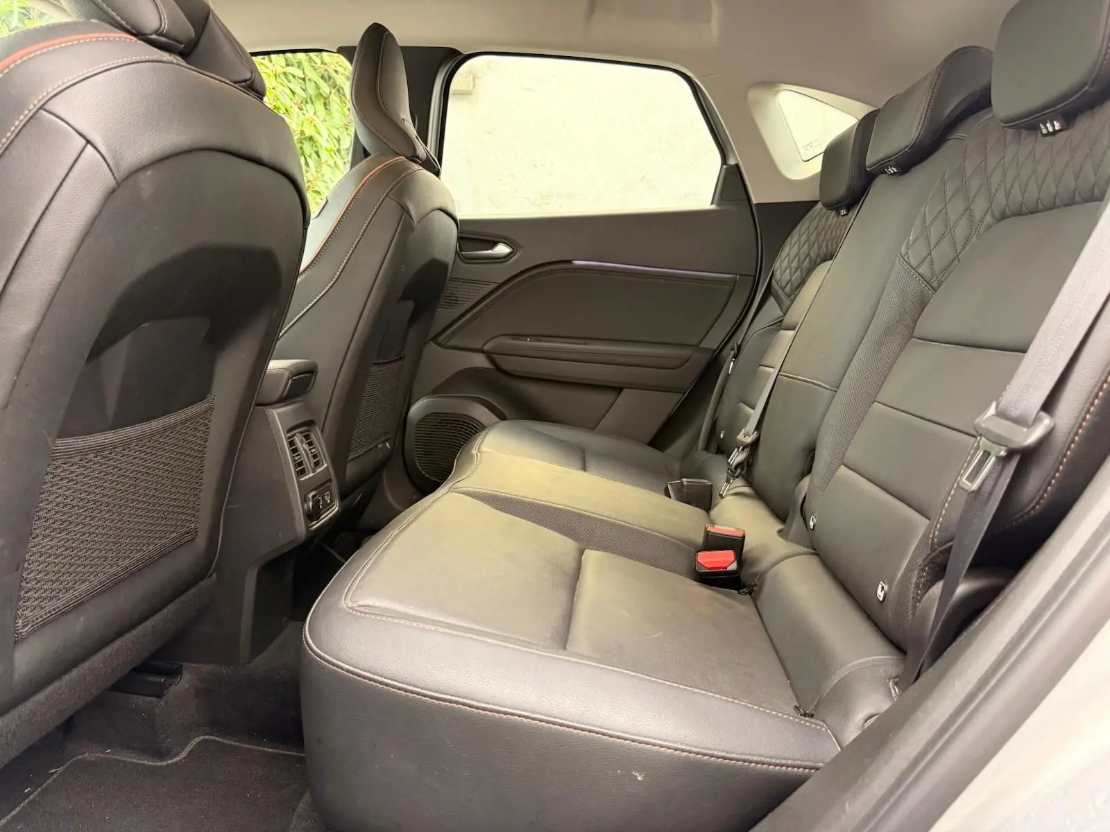 Vue intérieure côté droit des sièges arrière en cuir noir du Renault Captur hybride 2021, soulignant les finitions soignées.