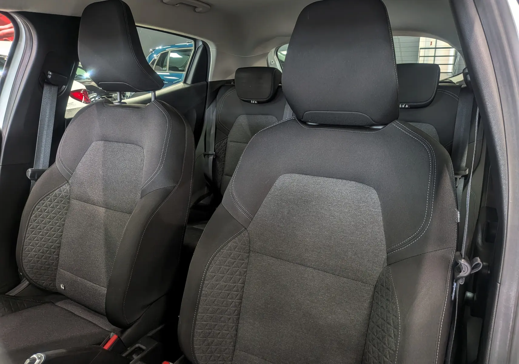 Vue intérieure rapprochée des sièges avant en tissu gris foncé de la Renault Clio V Business 2020 Blanc Glacier.