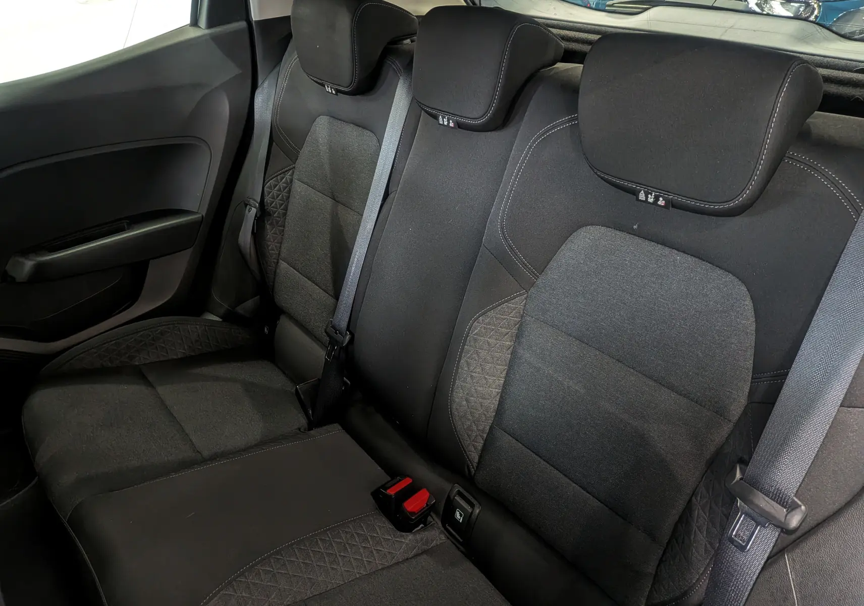 Vue intérieure des sièges arrière en tissu noir de la Renault Clio V Business, avec ceintures de sécurité visibles.