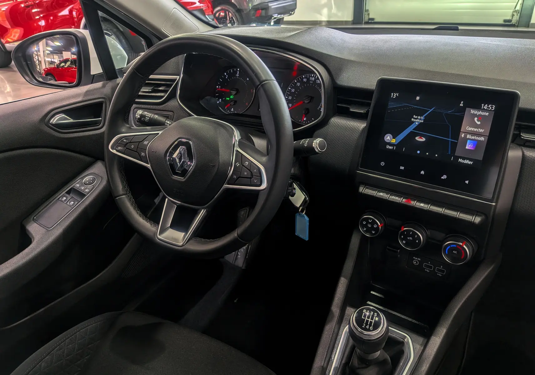 Vue intérieure côté conducteur de la Renault Clio V Business 2020, volant multifonction et écran tactile central allumé.