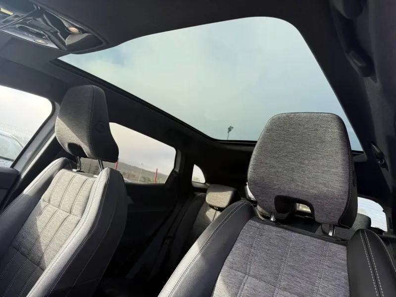 Vue intérieure du Renault Austral 2025 montrant les sièges avant gris et le toit panoramique en verre.