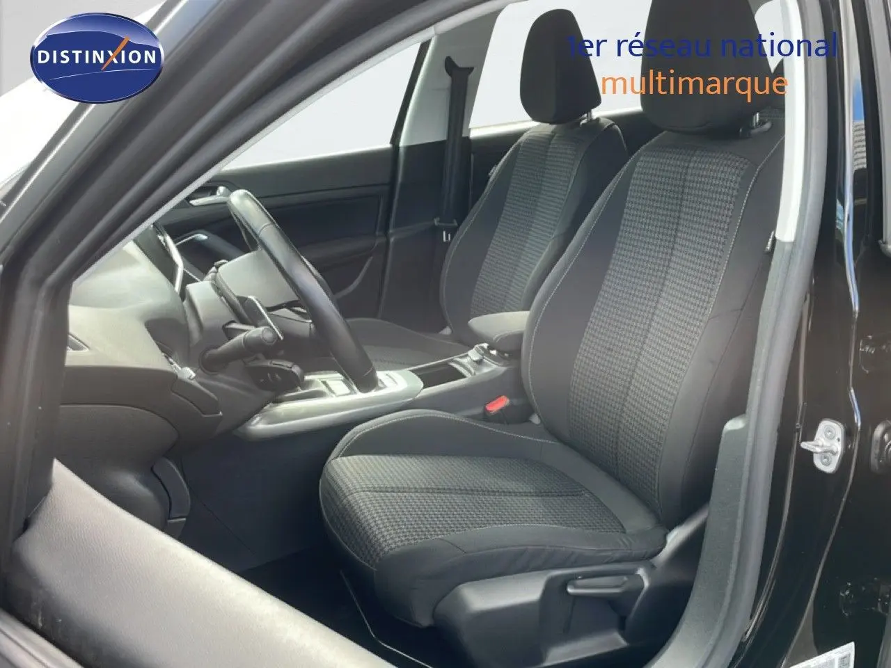Intérieur de la Peugeot 308 SW 2019 en noir, vue côté conducteur montrant les sièges tissu et le volant cuir.