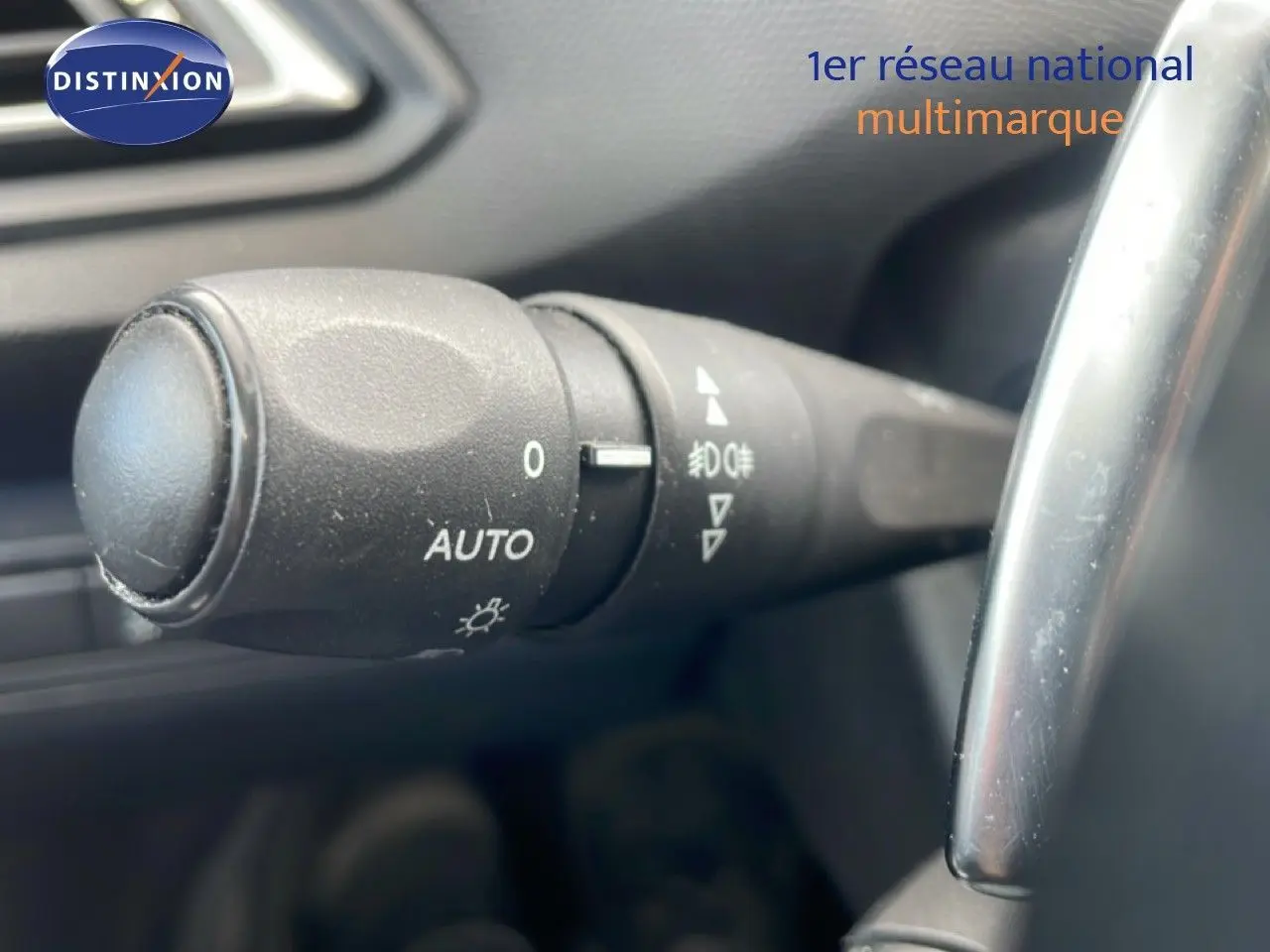 Gros plan sur la commande des phares avec réglage automatique dans l’habitacle d’une Peugeot 308 SW noire.