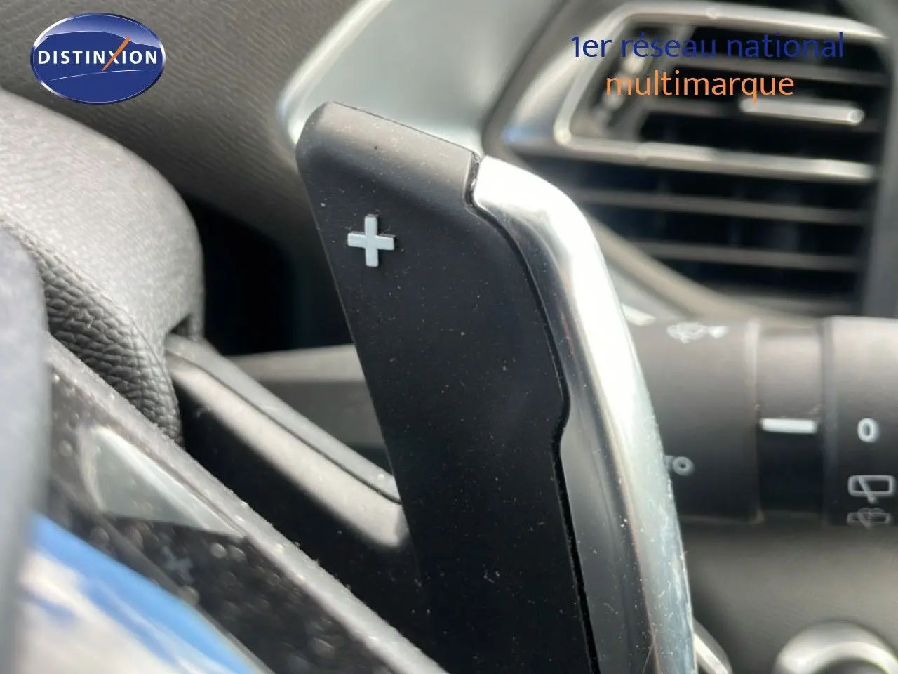 Gros plan sur la palette de changement de vitesse "+" côté droit du volant dans l'habitacle d'une Peugeot 308 SW noire.