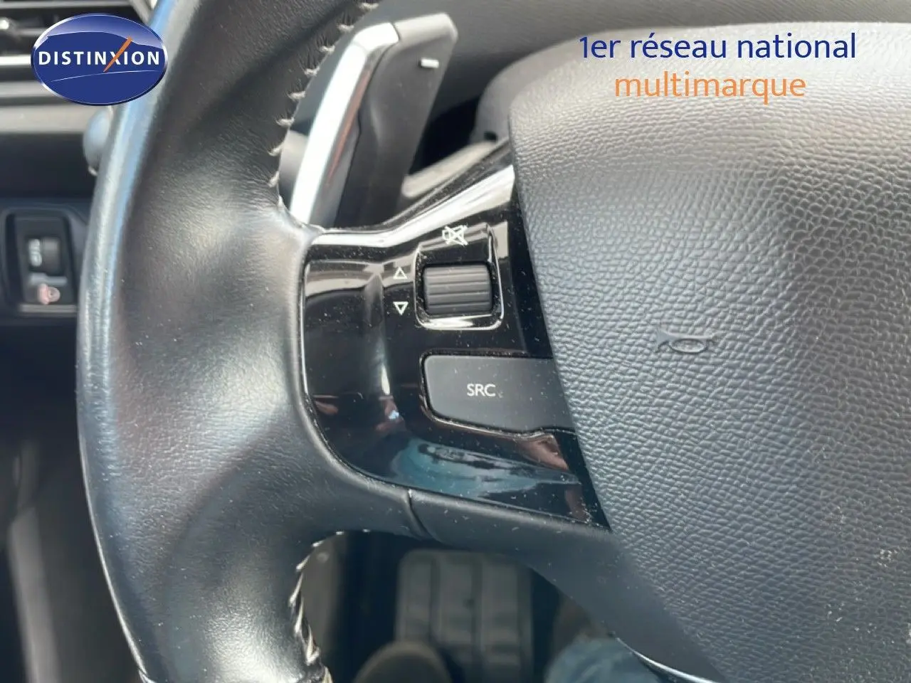 Gros plan sur le volant cuir noir de la Peugeot 308 SW 2019 avec commandes audio intégrées côté gauche.