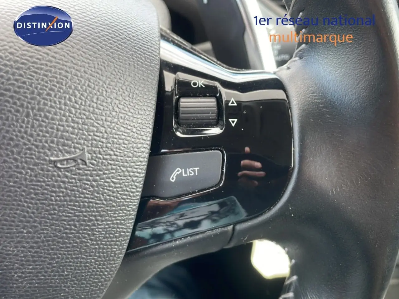 Gros plan sur les commandes au volant en cuir noir du Peugeot 308 SW 2019, avec boutons de gestion d’appels et menu.