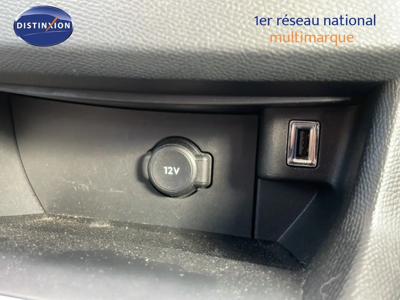 Prise 12V et port USB intégrés dans la console centrale d'une Peugeot 308 SW noire, vue intérieure rapprochée.