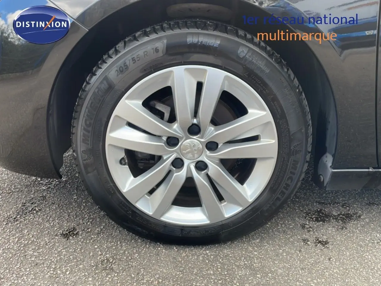 Gros plan sur la roue avant gauche d'une Peugeot 308 SW noire avec jante alliage argentée et pneu Michelin.