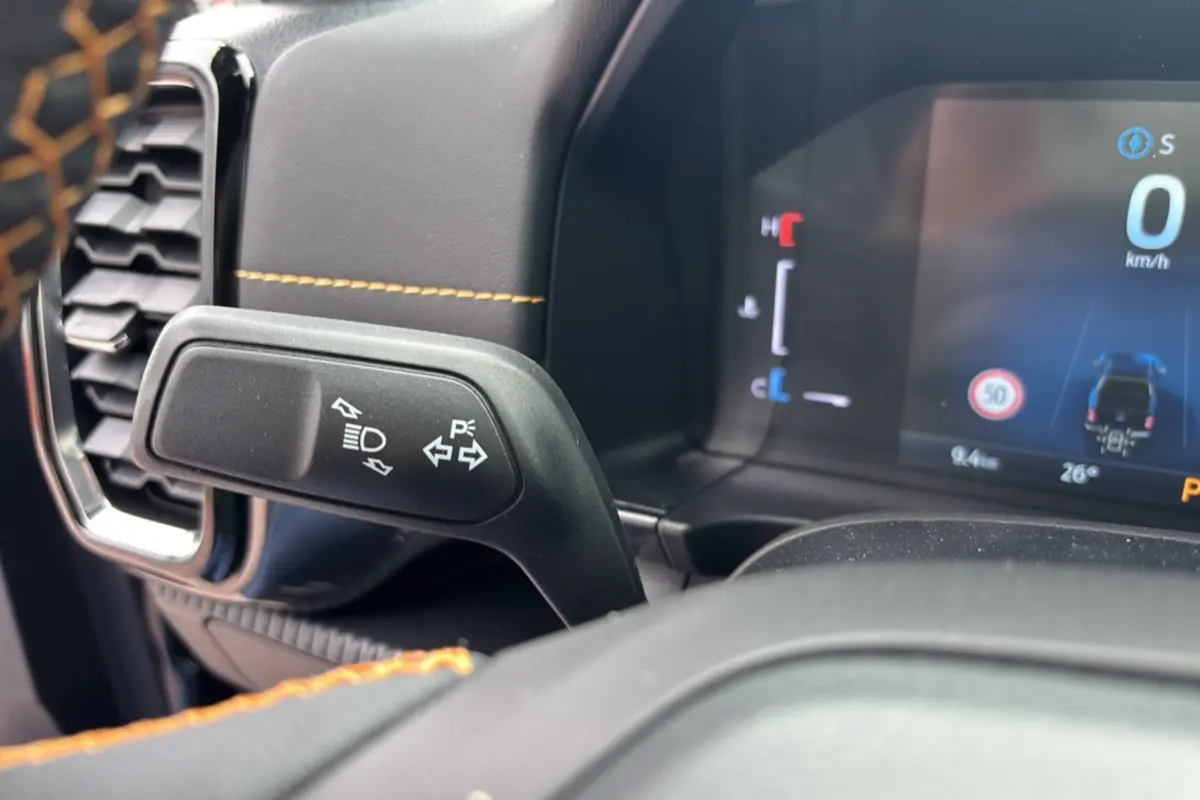 Gros plan sur la commande des clignotants et tableau de bord numérique du Ford Ranger Wildtrak Plus noir agate.