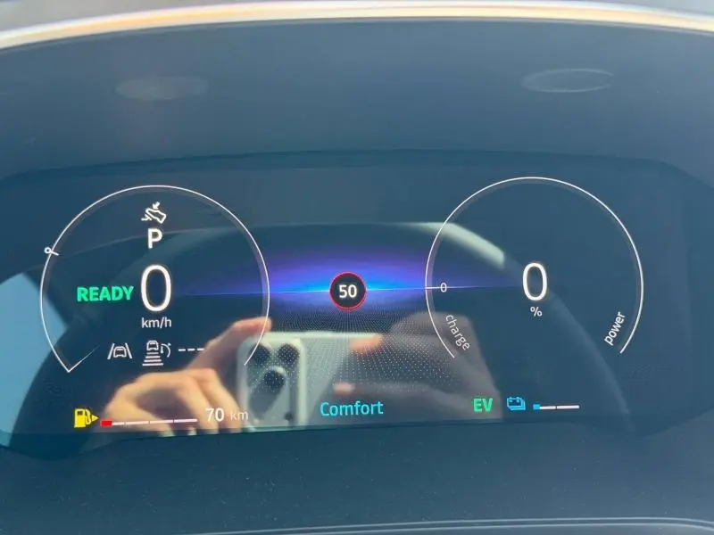 Tableau de bord numérique du Renault Captur blanc nacré, affichant vitesse, mode confort et autonomie hybride.