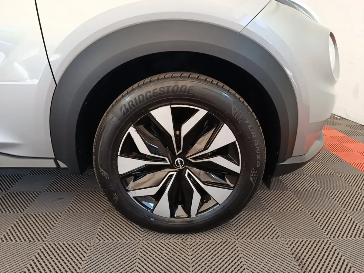 Gros plan sur la roue avant gauche du Nissan Juke gris clair 2023 avec jante alliage noire et argentée au design moderne.