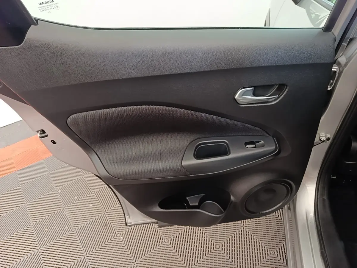 Vue rapprochée de la porte arrière droite gris clair du Nissan Juke 2023 avec poignée et haut-parleur intégrés.