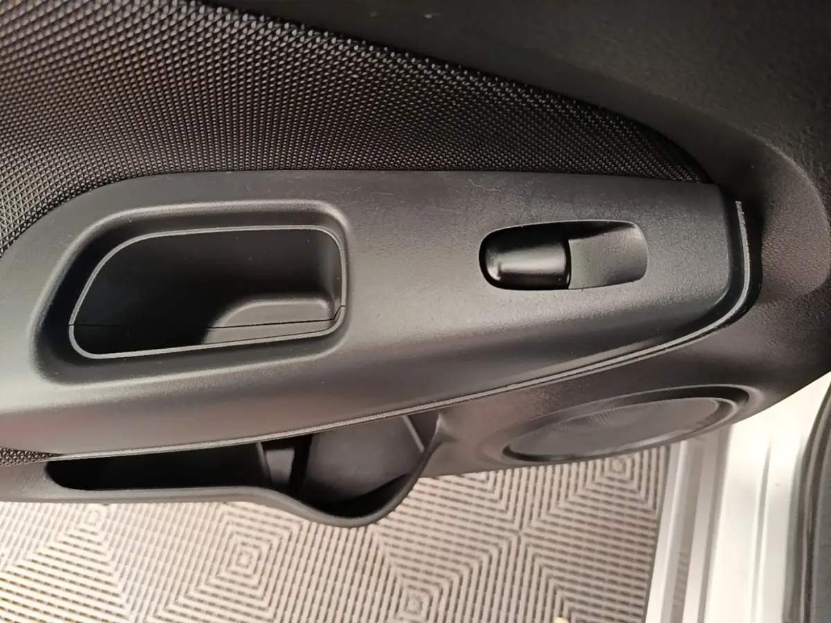Gros plan sur la poignée intérieure et commande de verrouillage de la porte côté conducteur d'un Nissan Juke gris clair 2023.