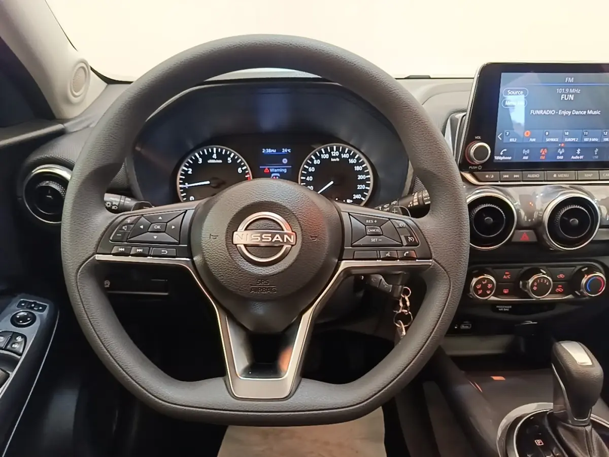 Vue intérieure centrée sur le volant noir du Nissan Juke 2023 avec tableau de bord et écran tactile visible à droite.