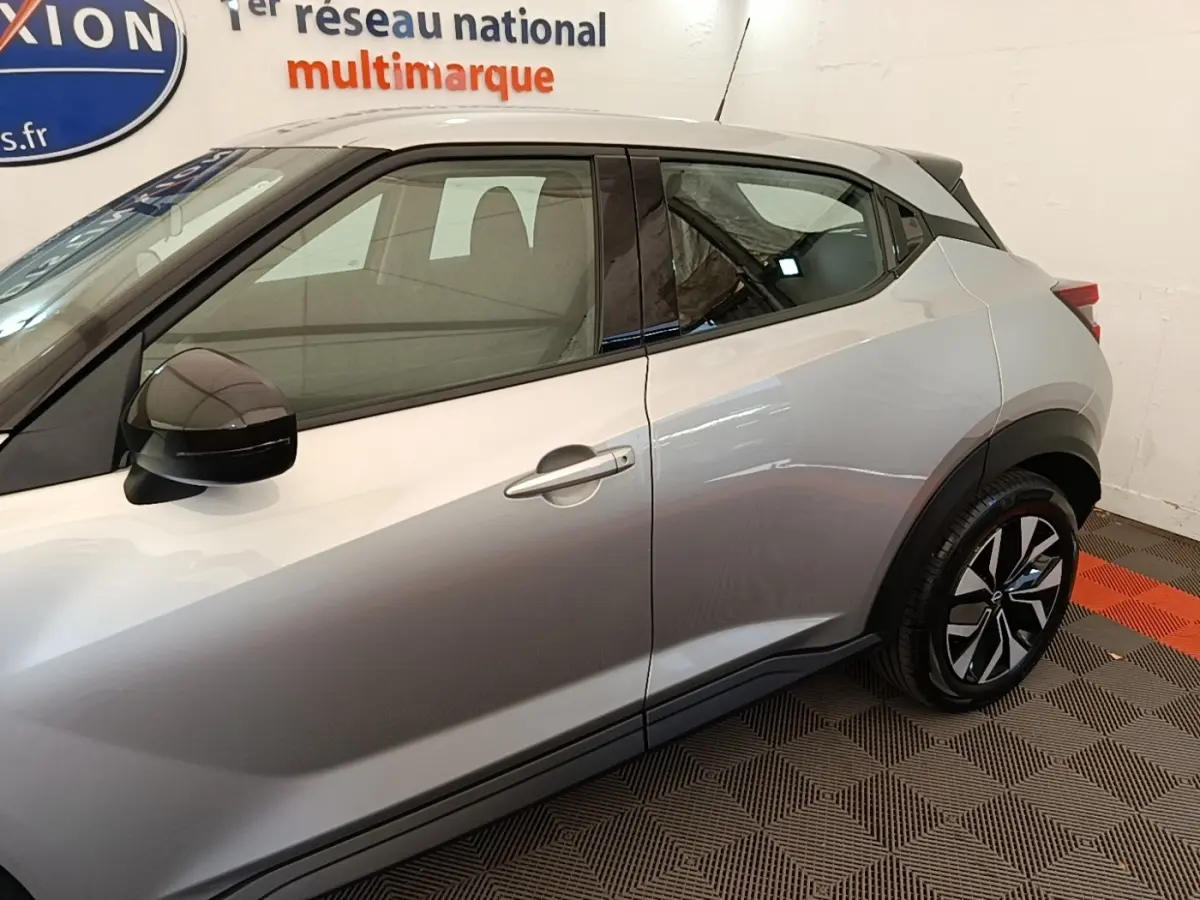 Vue côté droit du Nissan Juke gris clair 2023, mettant en valeur la ligne de caisse et les jantes noires à motifs.