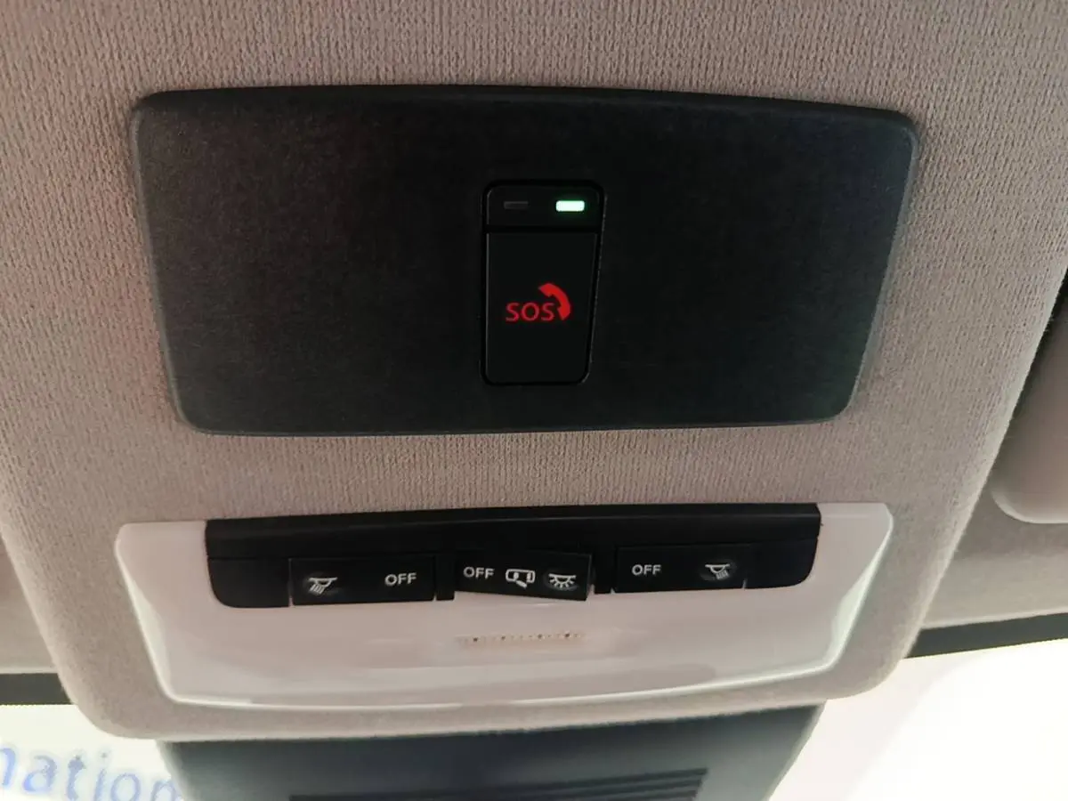 Gros plan sur le plafonnier intérieur avec bouton d'appel d'urgence SOS et commandes d'éclairage du Nissan Juke gris clair.