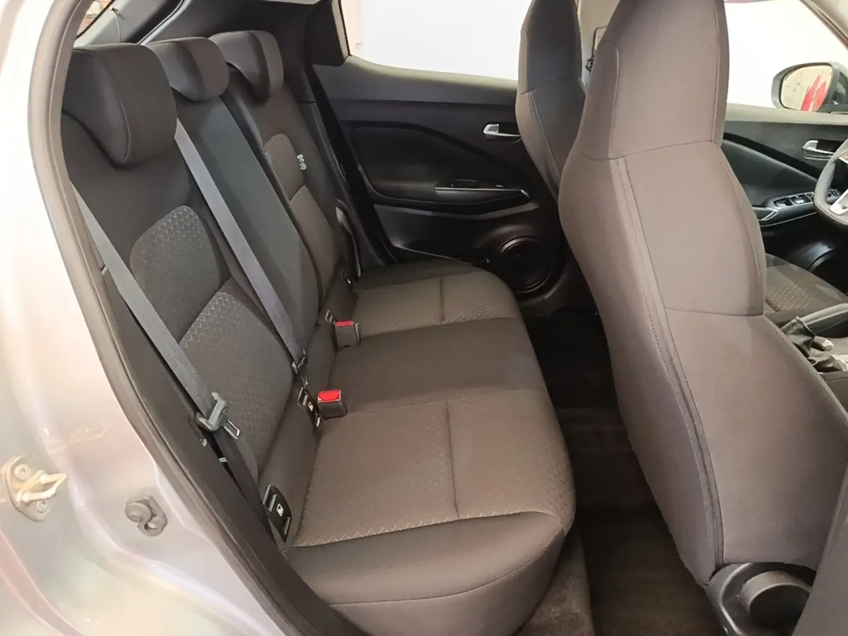 Vue intérieure côté gauche montrant la banquette arrière noire et les sièges avant du Nissan Juke gris clair 2023.