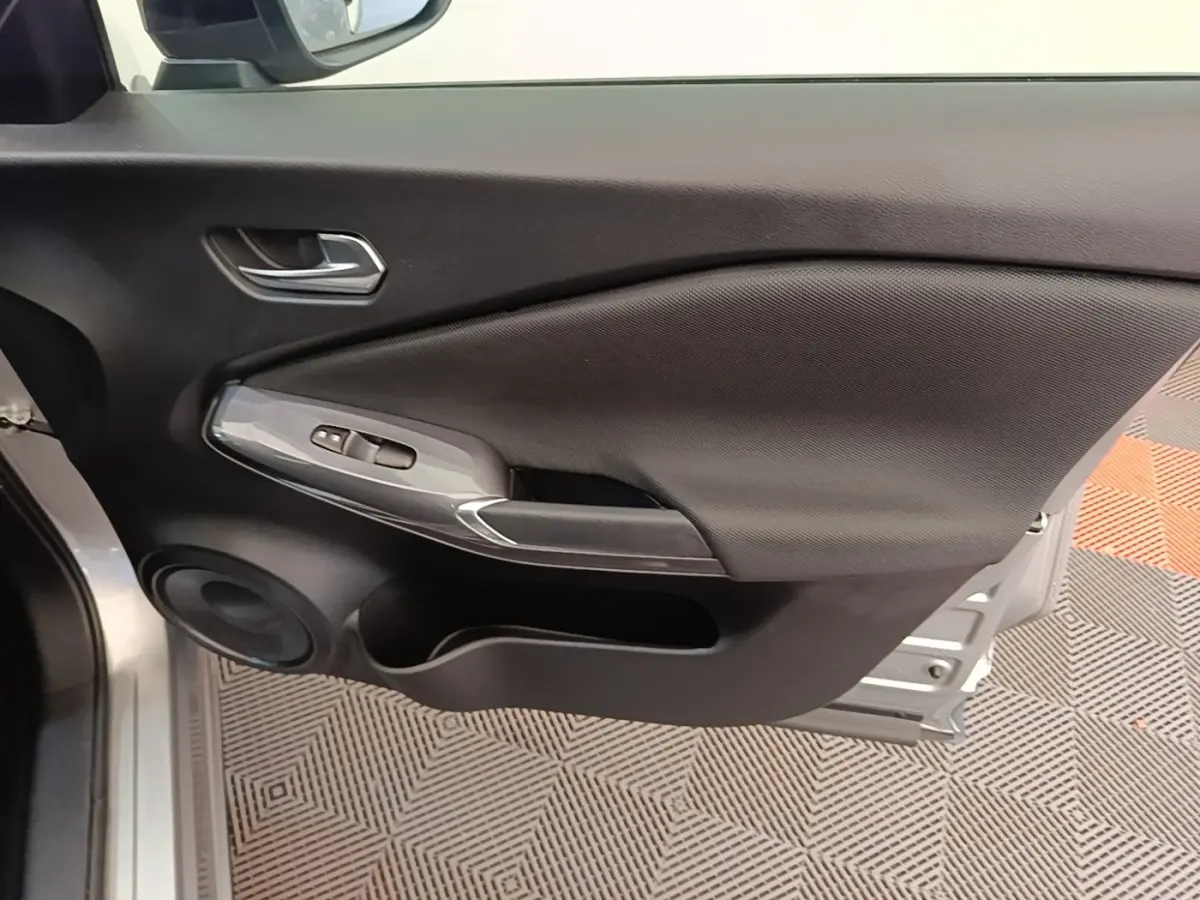 Vue rapprochée de la porte avant gauche gris clair du Nissan Juke 2023 avec commandes de vitres et haut-parleur intégré.