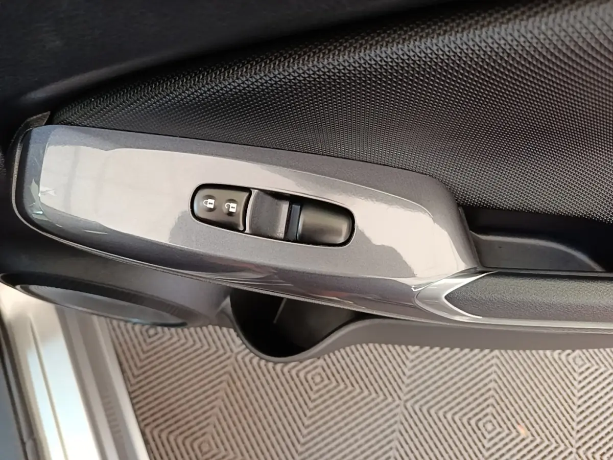 Détail de la commande de verrouillage centralisé sur la porte côté conducteur du Nissan Juke gris clair 2023.