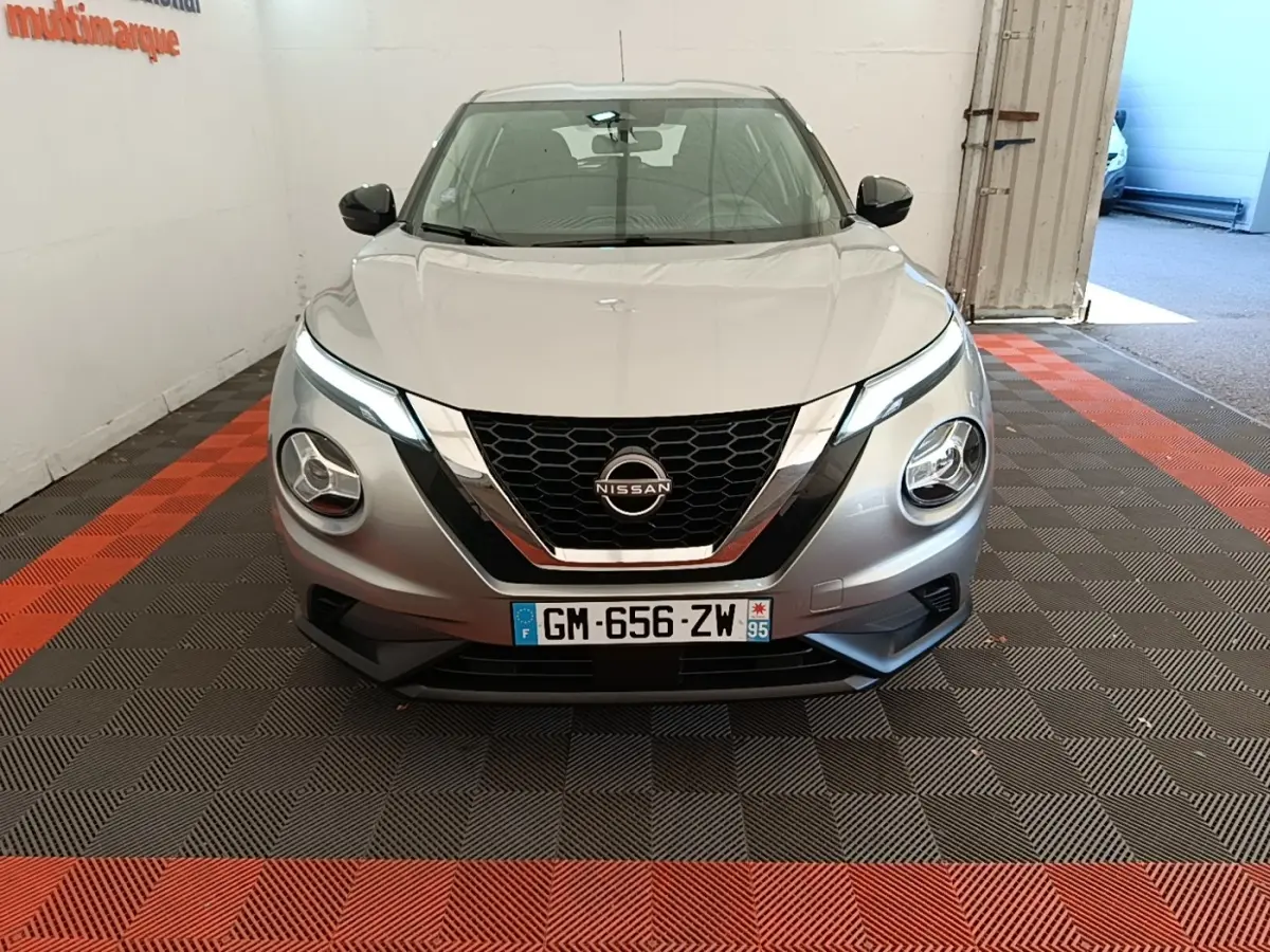 Vue avant frontale d’un Nissan Juke gris clair 2023 avec phares LED et calandre noire chromée.