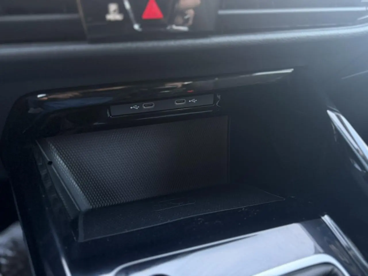 Gros plan sur le compartiment de rangement noir brillant avec ports USB-C dans une Volkswagen Golf VIII 1.5 TSI 130 Style 2024.