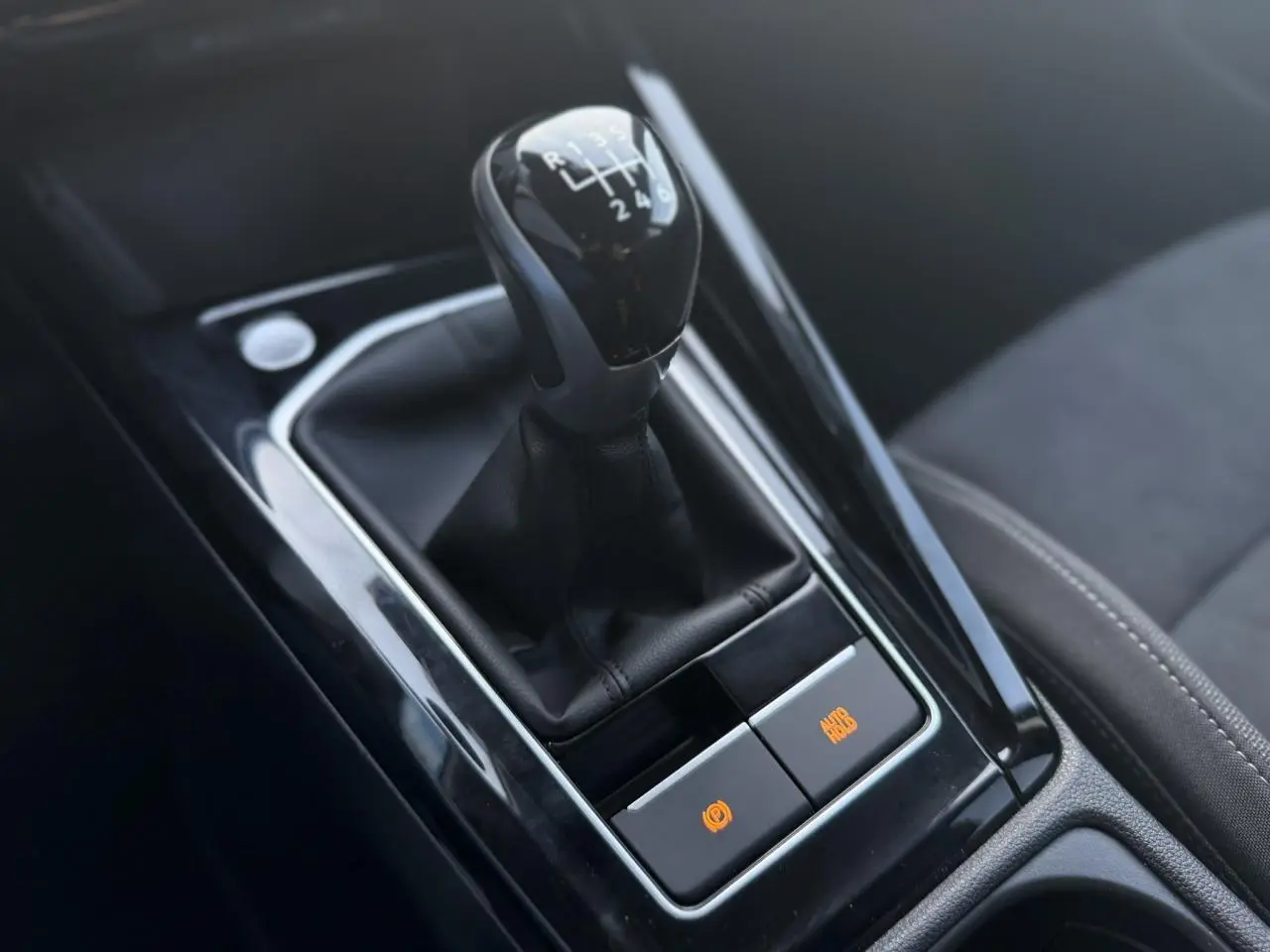 Gros plan sur le levier de vitesses manuel noir et la console centrale brillante de la Volkswagen Golf VIII 2024.