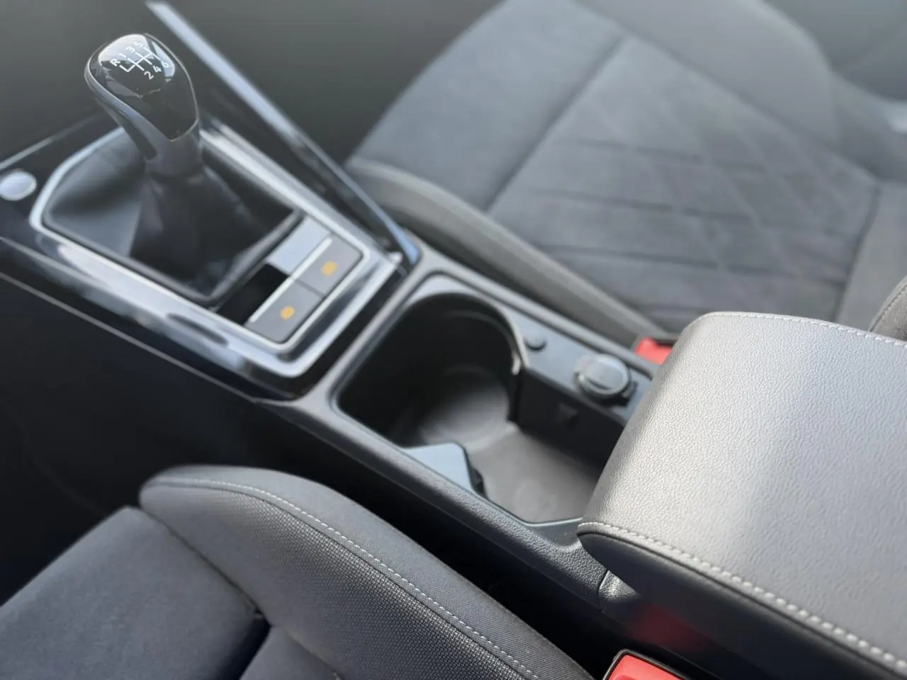 Gros plan sur la console centrale et levier de vitesses manuel de la Volkswagen Golf VIII 1.5 TSI Style 2024 avec sellerie microfleece noire.