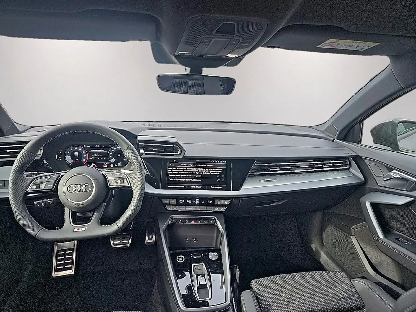 Vue avant de l’habitacle de l’Audi A3 Sportback 2026 avec tableau de bord noir et volant sport multifonction.