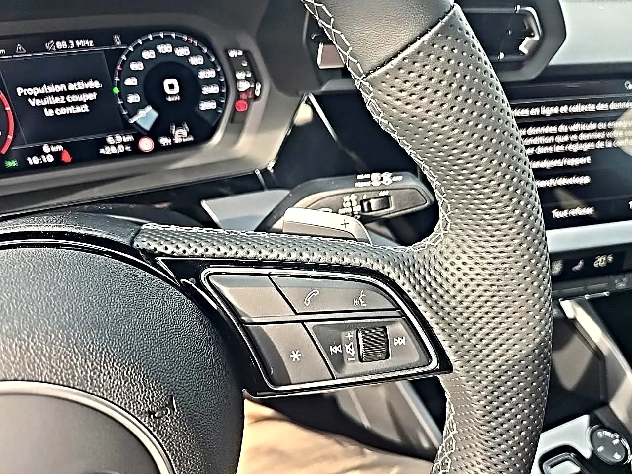 Gros plan sur le volant cuir perforé avec commandes multifonctions de l'Audi A3 Sportback 2026, intérieur noir.