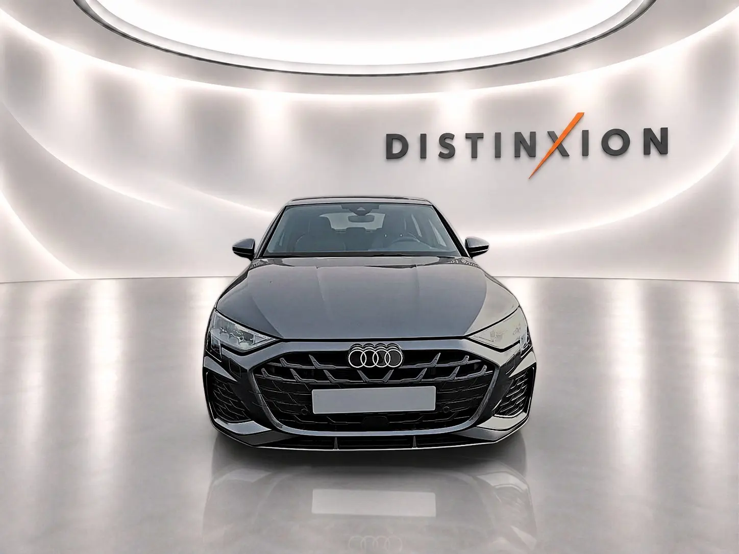 Audi A3 Sportback gris Daytona vue de face dans un studio lumineux avec logo Distinxion en arrière-plan.