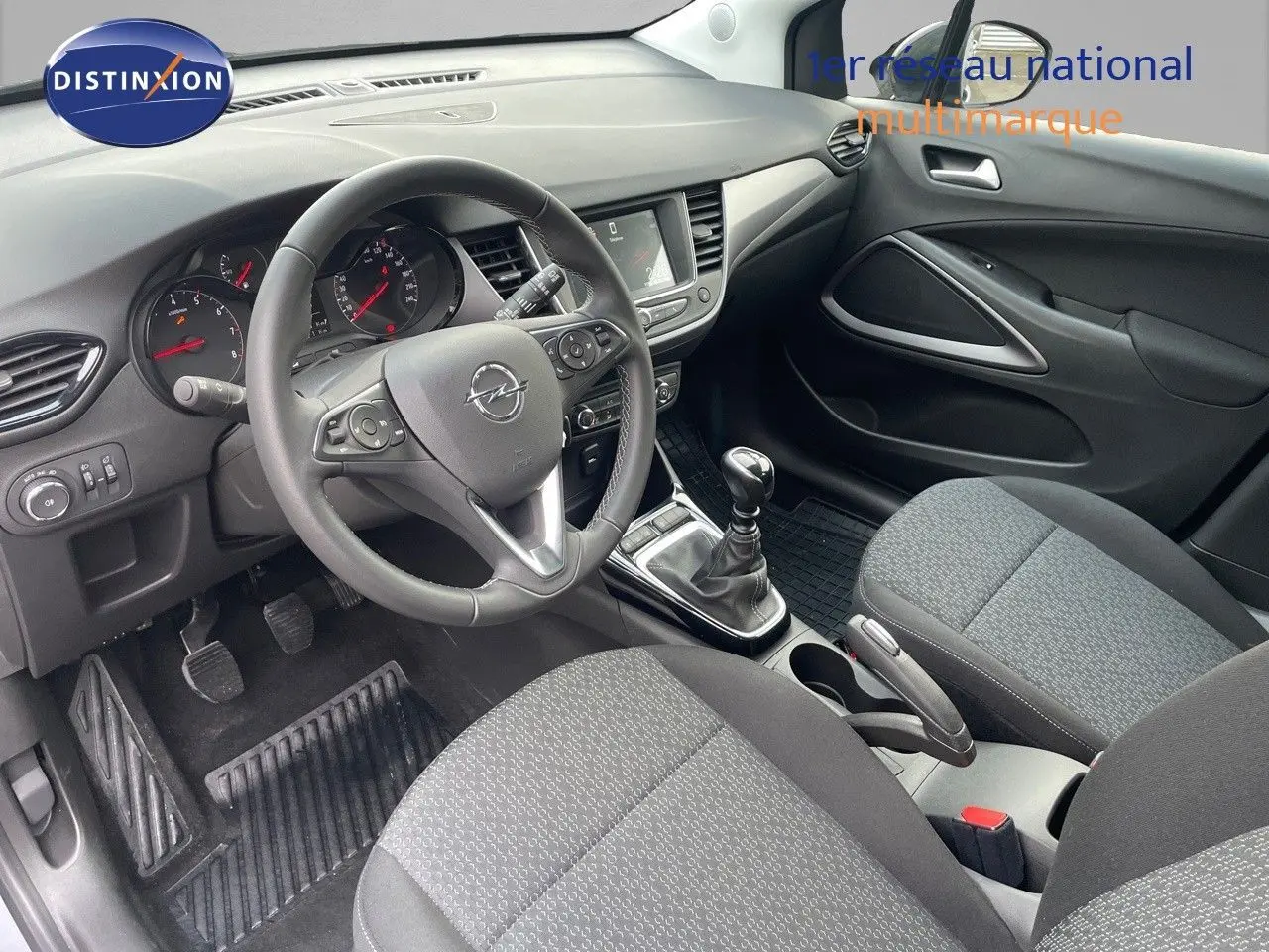 Vue intérieure côté conducteur de l'Opel Crossland 2022 avec tableau de bord noir et sièges tissu gris.