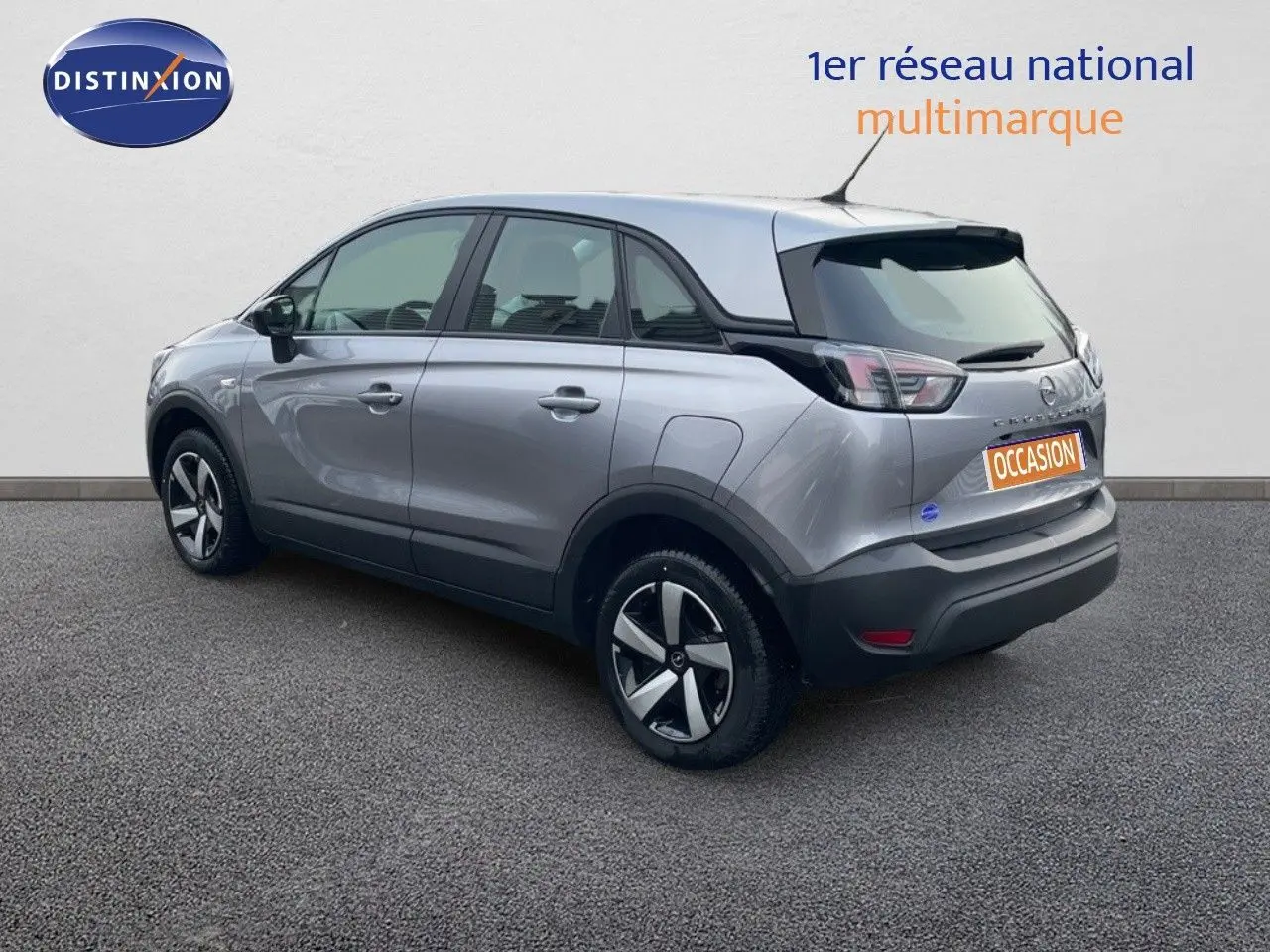 Opel Crossland gris minéral métal vu en 3/4 arrière côté gauche, avec jantes alliage et toit noir contrasté.