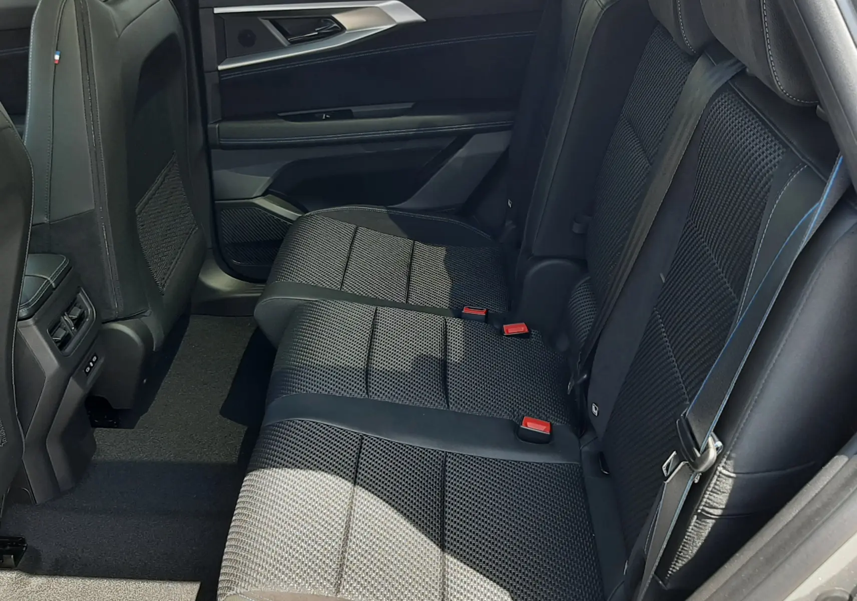 Vue latérale droite de la banquette arrière en tissu noir avec surpiqûres bleues du Renault Espace VI gris schiste métal 2025.