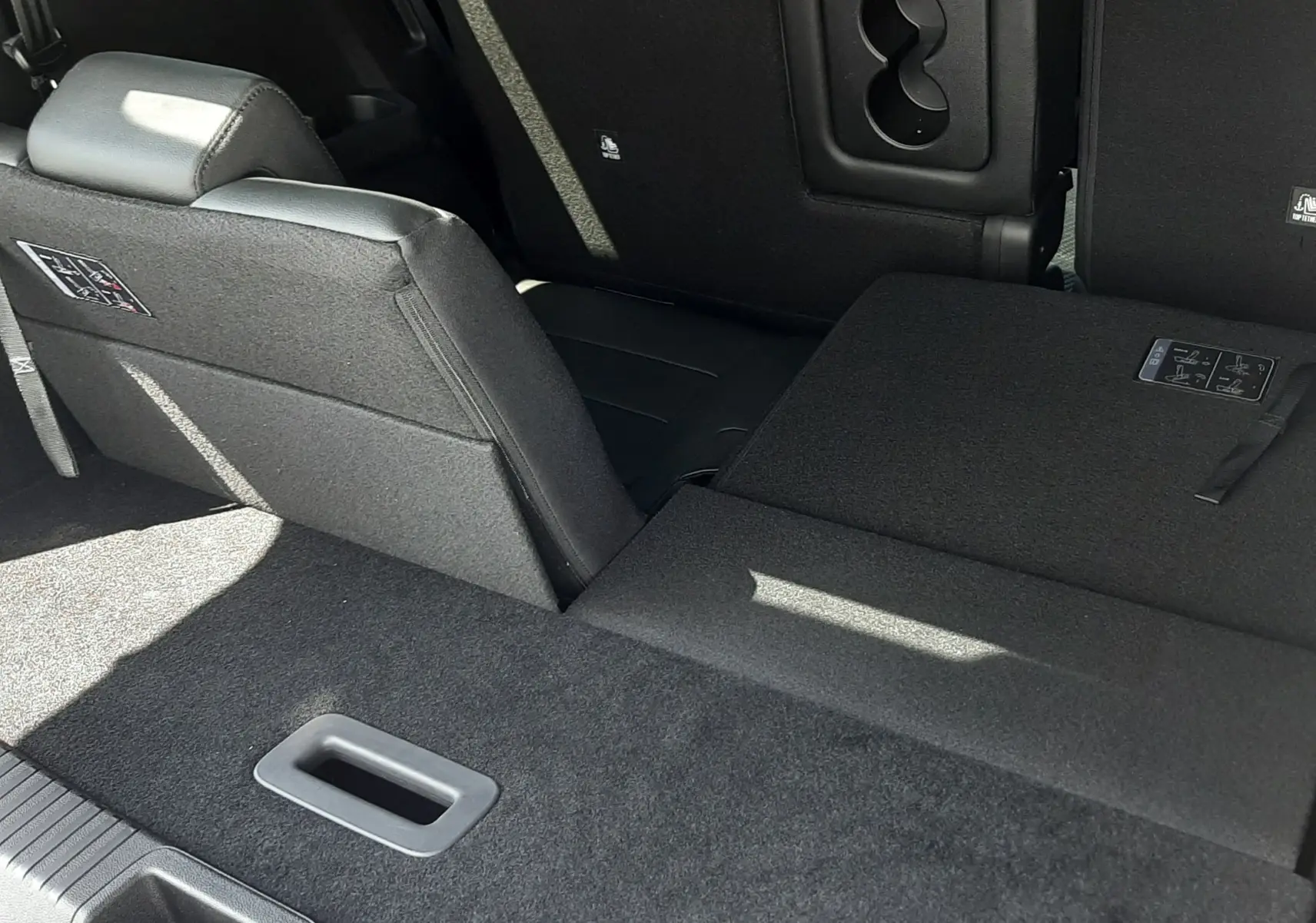 Vue intérieure arrière du Renault Espace gris schiste, montrant la banquette arrière partiellement rabattue et le coffre spacieux.