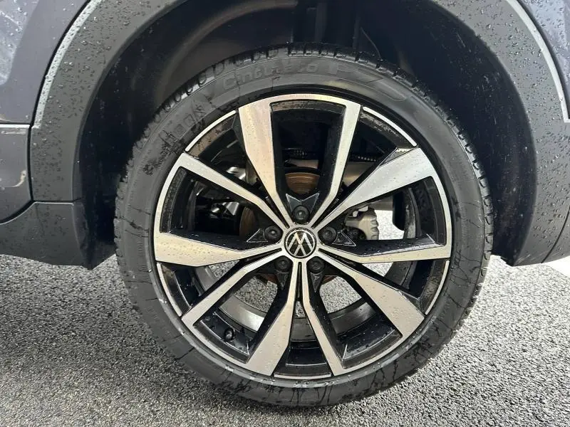 Gros plan sur la roue avant gauche du Volkswagen T-Cross 2025 gris Ascot avec jante alliage R-Line bicolore.