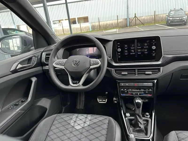 Vue intérieure côté conducteur du Volkswagen T-Cross Gris Ascot 2025, avec volant multifonction et écran tactile central.