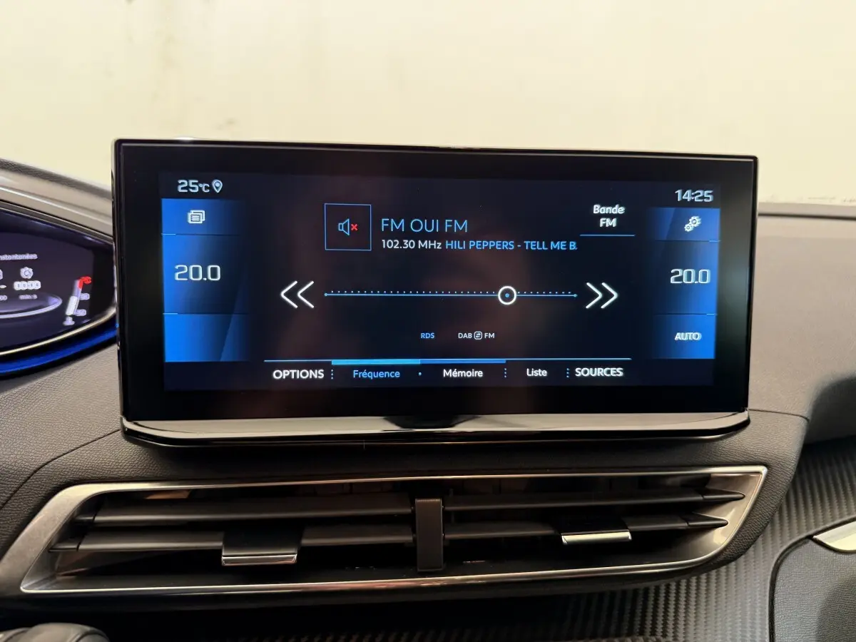 Écran tactile central du tableau de bord du Peugeot 3008 bleu, affichant la radio FM et la température à 20°C.