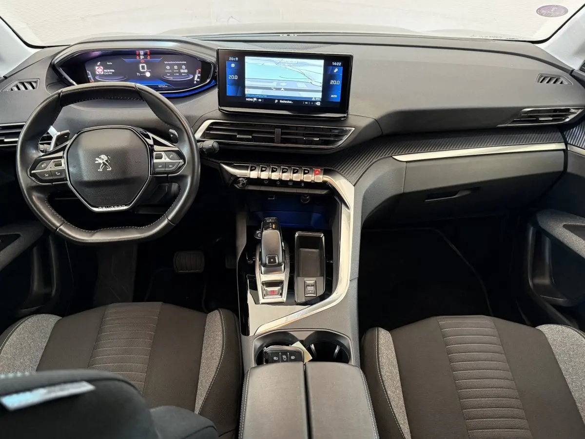 Vue intérieure avant du tableau de bord et volant cuir noir du Peugeot 3008 bleu, avec écran tactile central et commandes modernes.