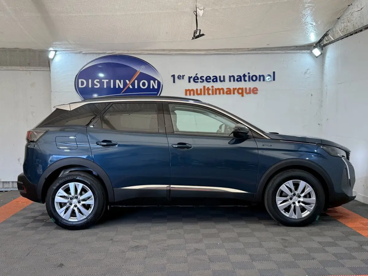 Vue latérale droite d’un Peugeot 3008 bleu 2021 version Style avec jantes alliage et rails de toit assortis.