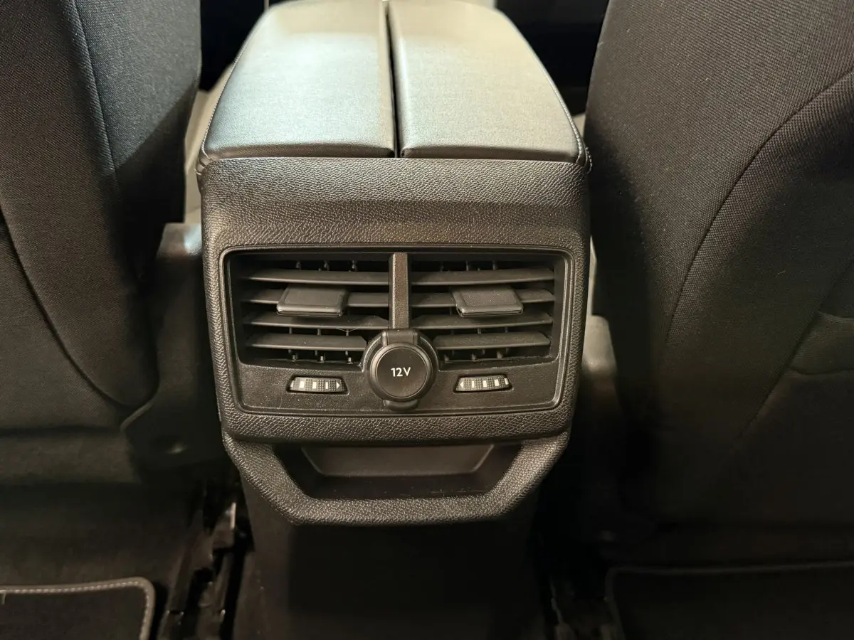 Vue rapprochée des aérateurs arrière et prise 12V entre les sièges noirs du Peugeot 3008 bleu 2021.