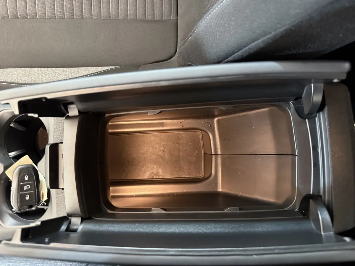 Vue plongeante sur la console centrale ouverte d’un Peugeot 3008 bleu, avec clé de voiture visible dans porte-gobelet.