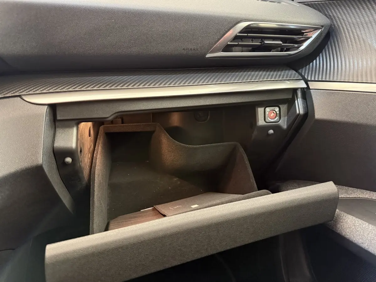 Vue intérieure du coffre à gants ouvert du Peugeot 3008 bleu, montrant la texture du tableau de bord et une lumière intérieure.