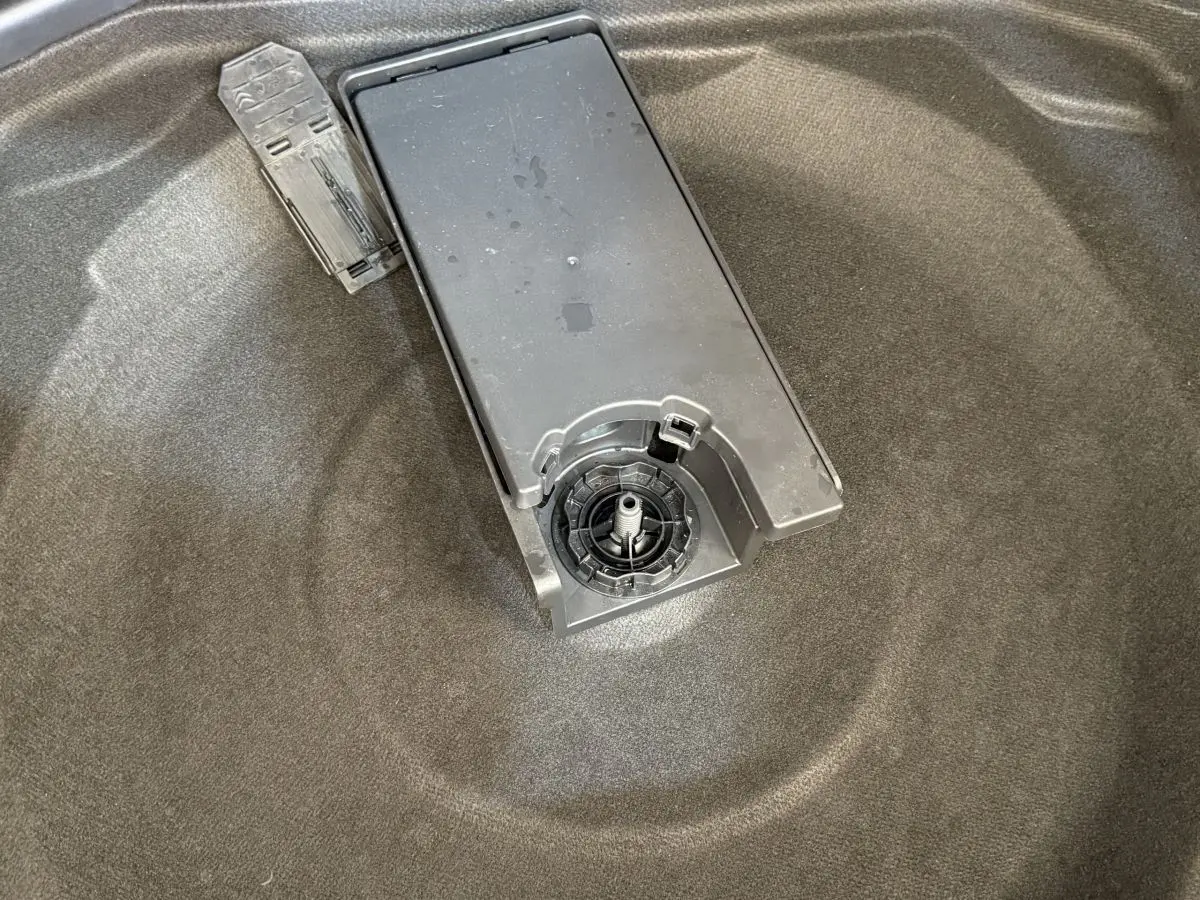 Gros plan sur le coffre gris foncé du Peugeot 3008, montrant le support de roue de secours et un outil plastique.